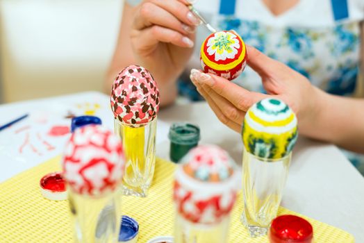 Woman paints the Easter eggs with a brush