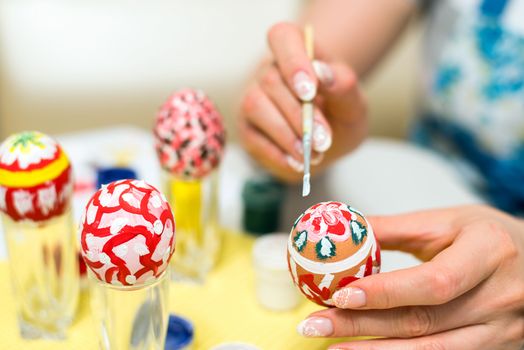 Woman paints the Easter eggs with a brush