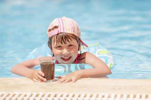 Little girl drinking soda in pool summer holidays