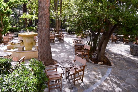 Shaded terrace with wooden chairs and tables for drinking aperitif