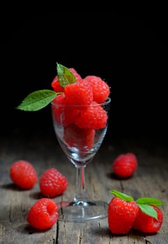 Raspberries in small glass on wooden table