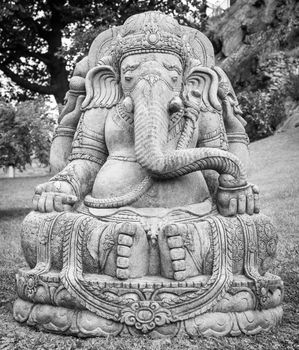 Ganesha statue, made of stone, with a beautiful mountain garden in background