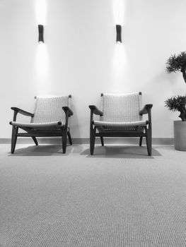Black and white interior with rattan chairs and carpet floor.