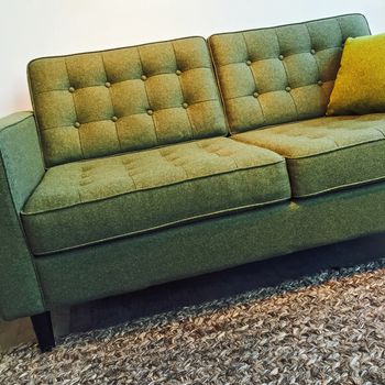 Retro style elegant green sofa on a knitted wool rug.