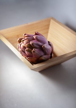 A fresh Artichoke in a square wooden plate