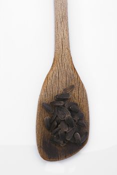 Sunflower seeds with wooden spoon isolated on white background.