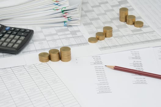 Brown pencil with step pile of gold coins on the statement finance account have blur calculator and overload of paperwork with colorful paperclip as background.