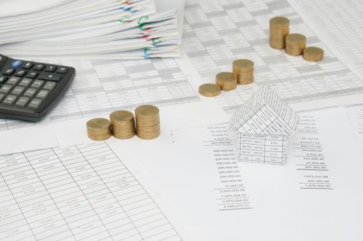 House with step pile of gold coins on the statement finance account have blur calculator and overload of paperwork with colorful paperclip as background.