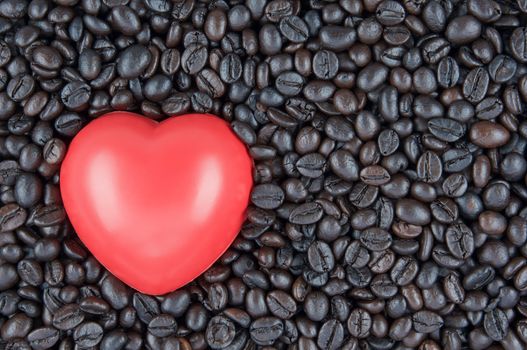 Red heart shape place on black roasted coffee beans use as texture or background.