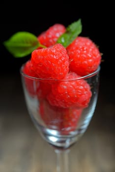 Raspberries in small glass on wooden table