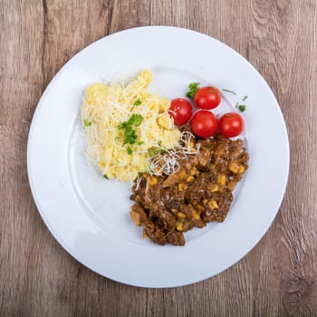 Vegetarian food on a white plate with wooden background