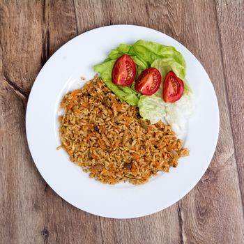 Vegetarian food on a white plate with wooden background