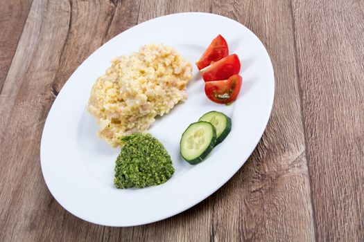 Vegetarian food on a white plate with wooden background