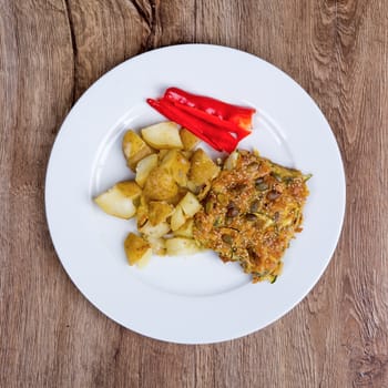 Vegetarian food on a white plate with wooden background