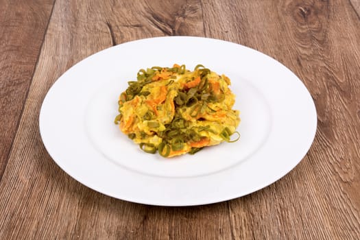 Vegetarian food on a white plate with wooden background