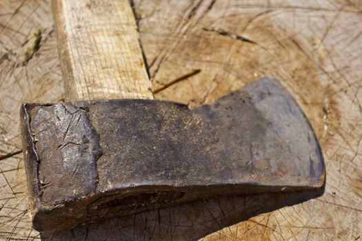 Old rusty ax against the background of a wooden stump