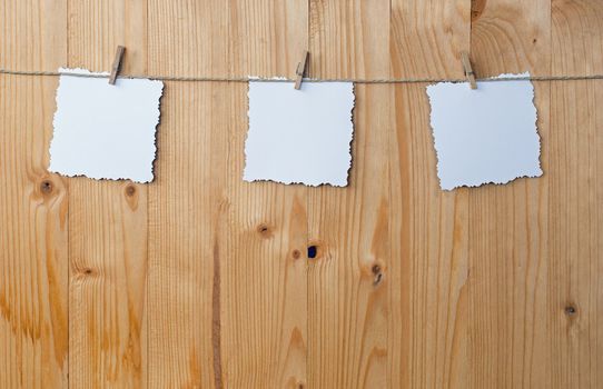 Three jagged note with clothes pegs on a cord on wood