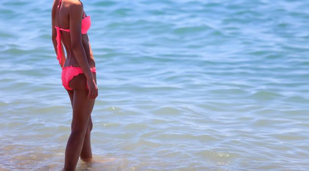 Slim woman with beautiful body in bikini posing on a beach