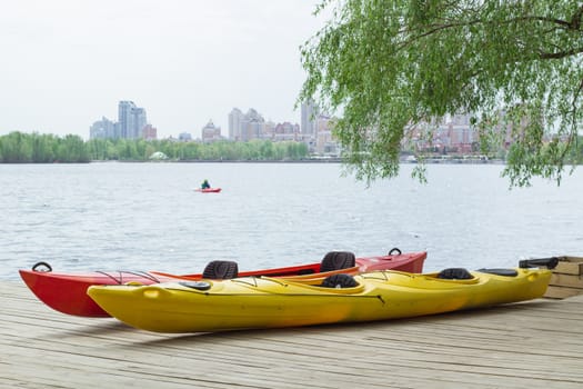 Two kayak boats on wooden deck at kayak station near river bank