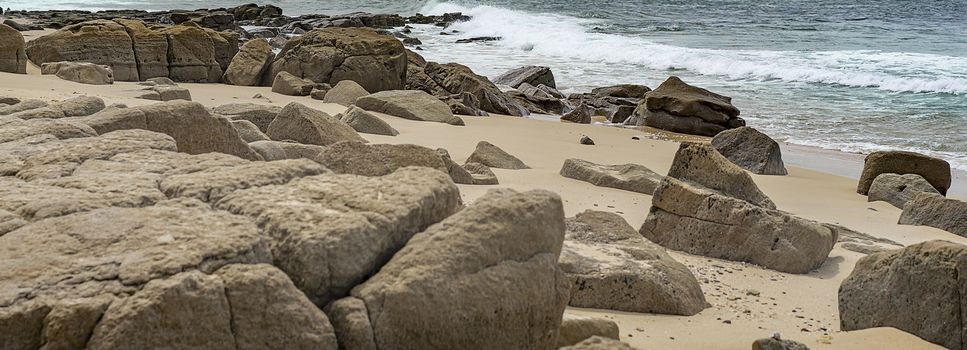 Australian panoramic rocky seafront beach view with rocks, boulders, sand, beach, surf waves and ocean