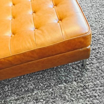 Fashionable leather seat on knitted wool carpet. Contemporary design.
