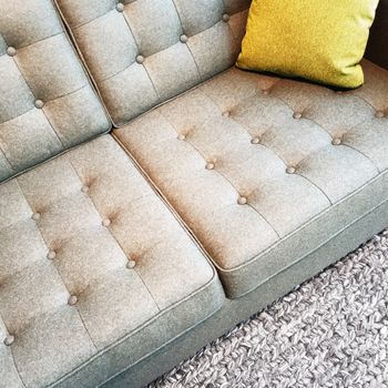 Gray textile sofa with cushion, on a knitted rug.