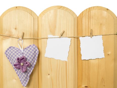 Two jagged note with clothes pegs and a checkered heart of fabric on a cord on wood