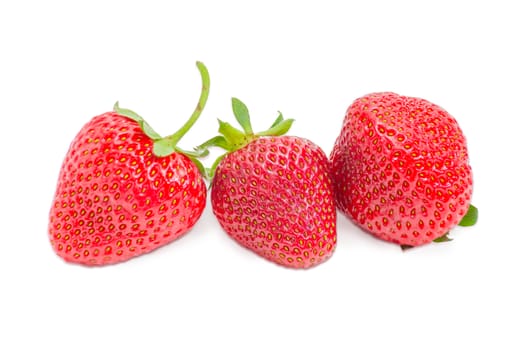 Three ripe fresh berries of the garden strawberry closeup on a light background
