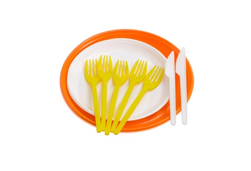 Orange and white disposable plastic plates different sizes, plastic disposable yellow  forks and white knives on a light background
