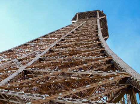 Bottom view closeup of the fragment of the top part of the Eiffel Tower in Paris
