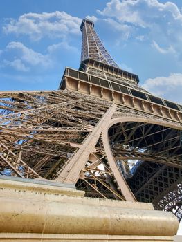 Bottom view closeup of the fragment of one of the legs and top part of the Eiffel Tower in Paris
