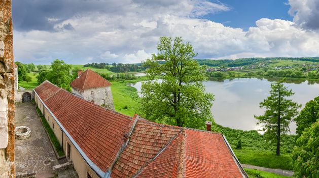 View from the window of the Svirzh Castle, built in the 15th century, on to the other castle buildings, lake and the surrounding countryside in springtime  in Lviv region, Ukraine
