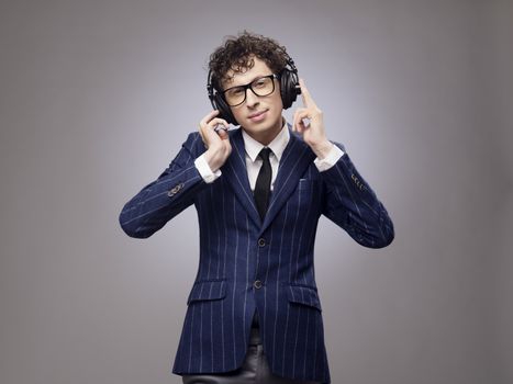 Funny man in headphones listening music, studio shot on gray background