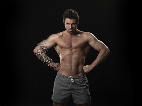 Portrait of brutal sexy muscular man with heavy chain on arm isolated on black background