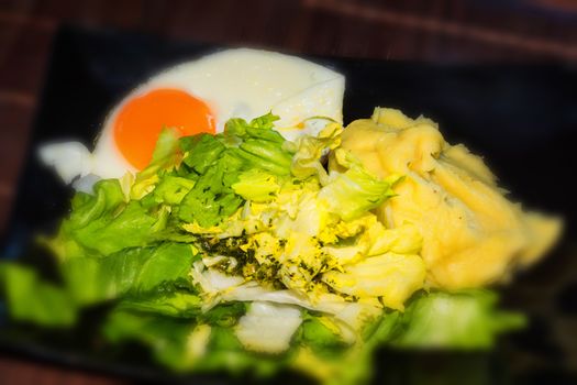 Fried egg in round shape on a white bread toast and black plate.