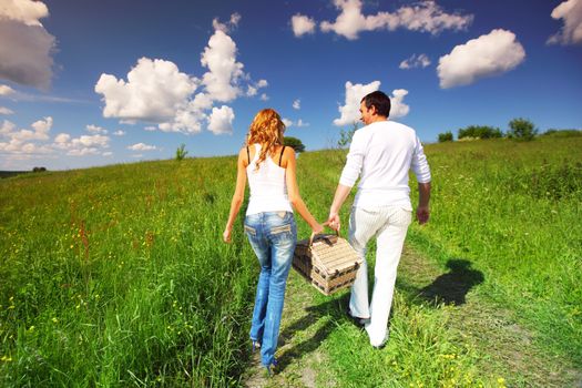 man and woman walk on picnic in green grass