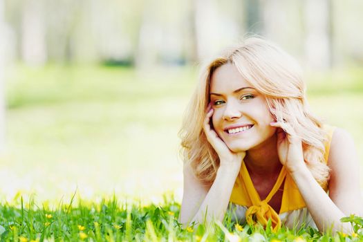 Smilng happy young woman lying on green grass meadow