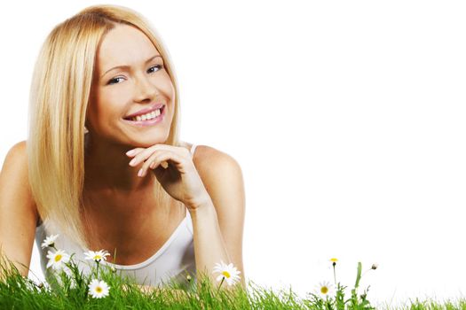 Beautiful young blonde woman lying on grass with chamomile flowers, isolated on white background