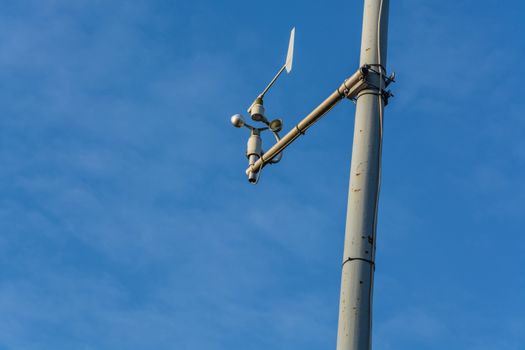 Weather station with anemometer on blue sky.