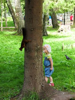 the girl in the blue suit feeding a squirrel in the woods