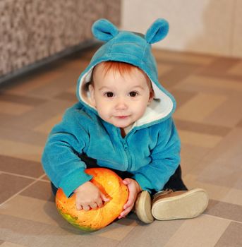 little boy of eight months holding not big orange pumpkin