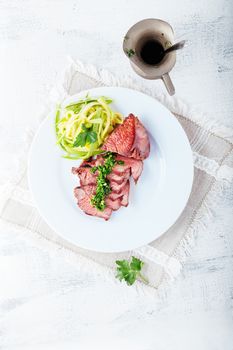 Zucchini pasta and meat on a white plate