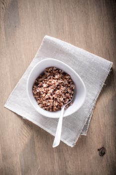 Boiled buckwheat in bowl on a woden surface