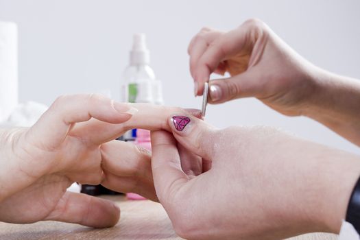 Professional manicure procedure in beauty salon. Hands close up.