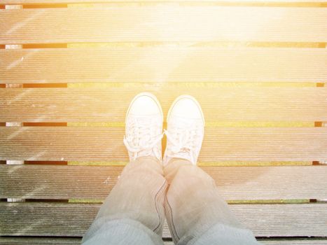 Selfie of woman white sneaker shoes stand on wooden bridge background with copy space, top view