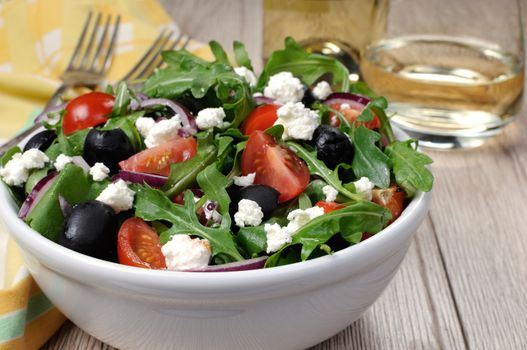 Variation of Greek salad with arugula, cherry slices, feta and olives