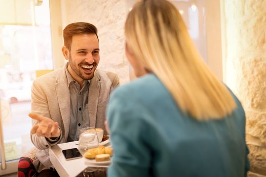 Young smiling businesspeople on a break in a cafe. They are drinking coffee and talking with smile. Selective focus.