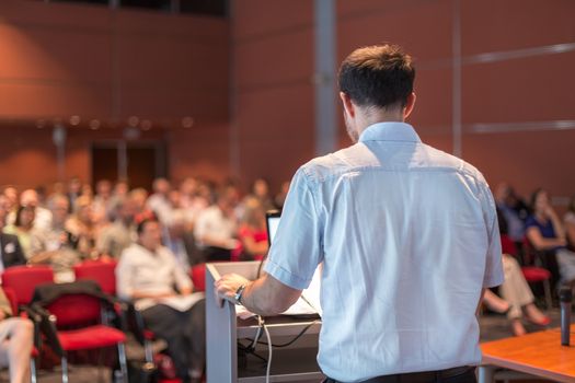 Casualy dressed professor giving talk at scientific conference. Audience at the conference hall. Research experts and entrepreneurship event.