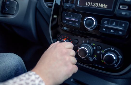 male hand pressing button in modern car. Man adjusts the temperature of the car air conditioner