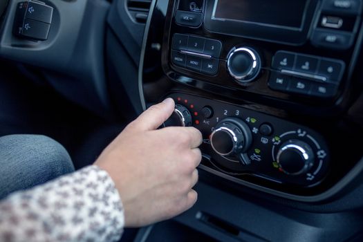 male hand pressing button in modern car. Man adjusts the temperature of the car air conditioner